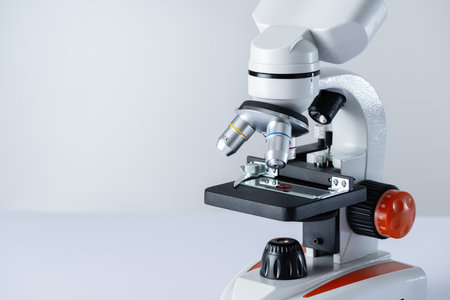 Microscope on white background with copy space. Blood sample on a glass under microscope. HIV test...