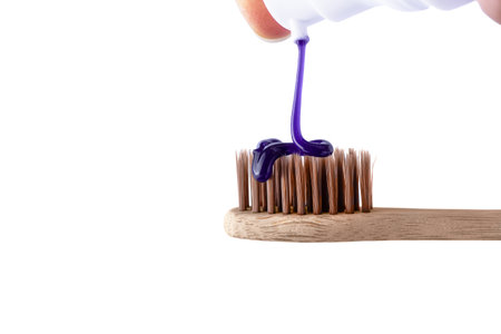 Pouring a whitening purple toothpaste on a toothbrush isolated on white background. Texture of purple tooth gel for whitening teeth, plastic free concept.の写真素材