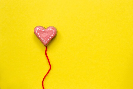 Heart shaped sugar cookie on yellow background. Valentines day card concept.