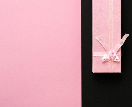Close up shot of small elegant pink gift box on pink and black textured background. Minimal concept. Flat lay. Top viewの写真素材