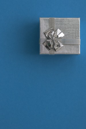 Silver gift box over blue background. Close up. Copyspaceの写真素材