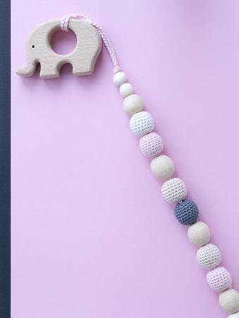 Necklace made from knitted beads and wooden toys for the baby sitting in a sling. Knitted beads.の写真素材