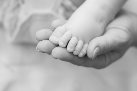 Mother holding baby feet in hands. Soft focus.の写真素材