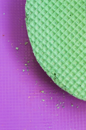 Colourfull green waffles on purple desk. Textured abstract background. Close up. Flat layの写真素材