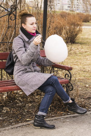 Portrait of pretty fashion blondie european woman eating sweet cotton wool. Student or young enterpreneur with black backpack.の写真素材