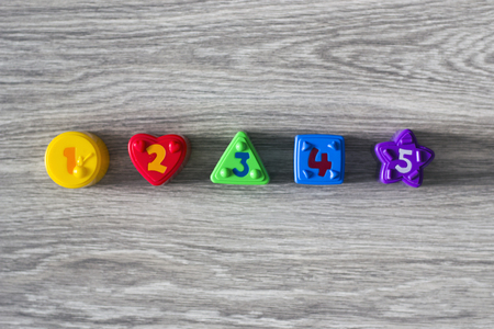 Colorful plastic shapes with numbers on a wooden background. Flat layの写真素材