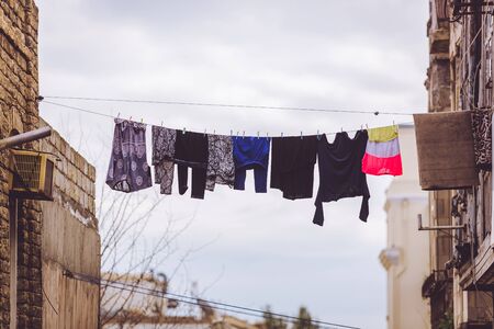 Clothes drying on a rope outdoors between the walls of houses in a southern countryの写真素材