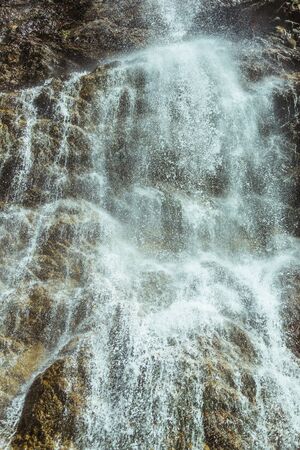 Streams of mountain waterfall close up, view from below. Wild jets and spray