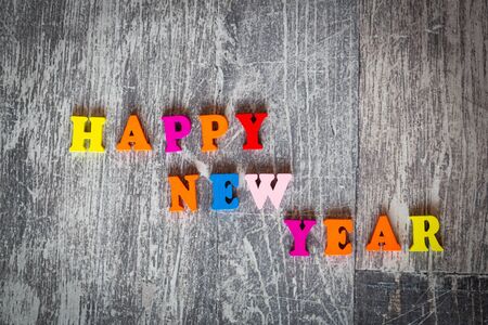 Multicolored inscription Happy New Year on a wooden background. Pink, orange, blue, red, yellow...