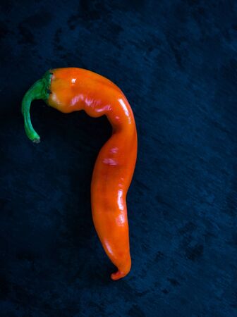 Bright orange hot chili pepper on a dark blue stone background. Free space for textの写真素材