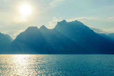 Seascape. Dramatic sunset with mountains view on Lake Garda, Italy. Colorful sky, clouds and water surface. Travel destinationsの写真素材