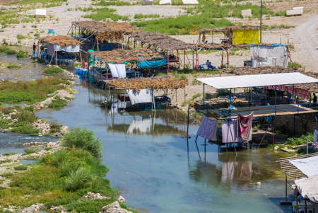 Hasankeyf, Turkey, 08.23.2014: The view of the Tigris River valley and various cafes right in the river water under awnings. Escaping from the heatのeditorial素材