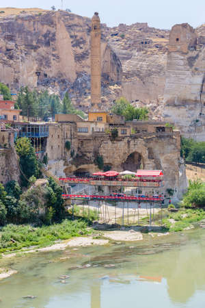 Hasankeyf, Turkey, 08.23.2014: The view of El Rizk Mosque and Minaret on the bank of the Tigris River. The cafe over the river with the old city in the backgroundのeditorial素材