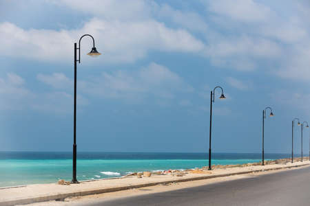 The road along the turquoise sea. Lebanese Mediterranean coastline. Street lights on the waterfront in Lebanon. Sea water of amazing color. The coastland between Sidon and Beirutの写真素材