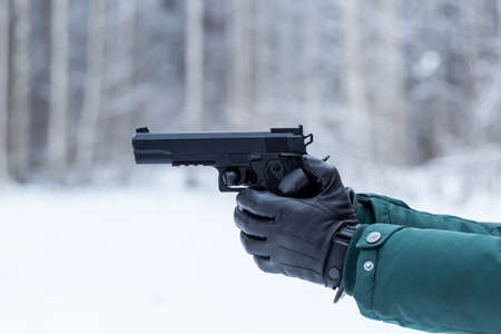 Gun in hand. Black leather gloves with a pistol. Shooting in nature.の写真素材