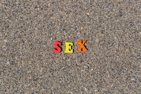 Multicolored inscription Sex on the sand. Yellow, red, orange wooden letters. Romantic caption for a honeymoon. Colorful word sex on the beach in the sunlightの写真素材