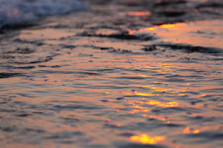 Wave splash at sunset close up. Ocean water in sunlight in motion. abstract sea backgroundの写真素材