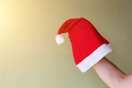 Santa hat in hand. Red santa caps in the sunbeams. Christmas and New Years concept. Celebrating the new year at the hotel on the beach.の写真素材