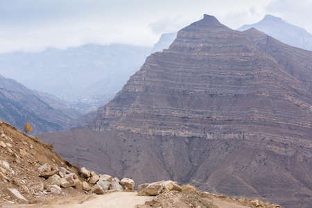 Rocky road in the mountains. Blocks of stones on the path. Dirt road among the peaks. Panoramic landscape view in Dagestan, Russiaの写真素材