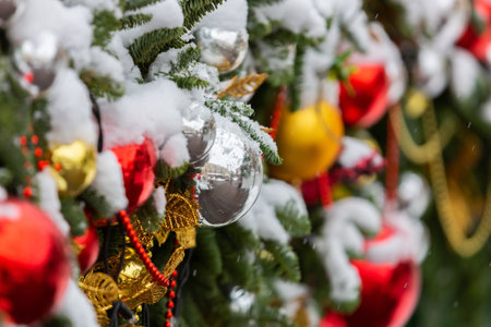 Christmas balls on a fir branch in the snow. Beautiful bokeh. Blurred background with glass red and yellow balls in snow. Winter festive background for New Year designの写真素材