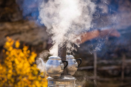 Teapot steamed on a fire in the mountains. Autumn camping. Boiling tea, coffee, water in nature outdoors. Cooking in the tent. A boiling kettle on a hike.の写真素材