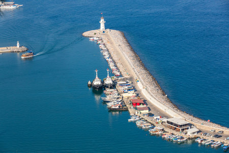 Alanya, Turkey, 09.07.2021: View of the Alanya Lighthouse and the stone embankment. Pier with ships and pleasure boats. Alanya bay view from aboveのeditorial素材