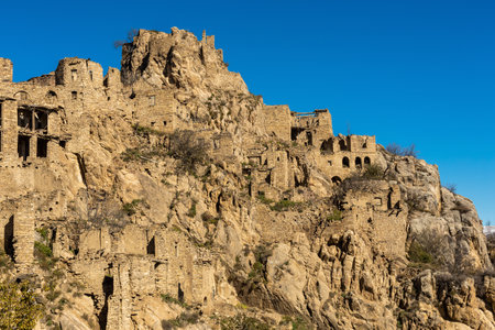 Ghost town of Gamsutl, Dagestan, Russia. Abandoned houses on the backdrop of blue sky. Panoramic view of stone wallsの写真素材