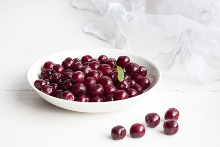 Burgundy cherries in the white saucer on the window-sill. The gifts of summer.の写真素材
