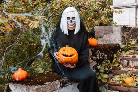 Portrait of scary woman with skeleton makeup and carved pumpkin.の写真素材