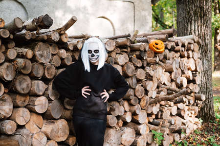 Portrait of dead bride, who is standing near the sawn logs. Next to the carved pumpkin for Halloweenの写真素材