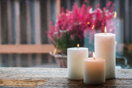 White burning candles on wooden table with bokeh and blurry background.の写真素材