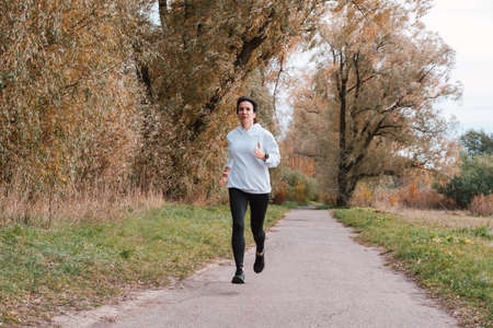 Outdoor photo of a sporty woman running in a park.の写真素材