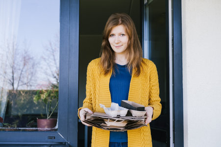Woman leaves the house with sorted garbage.の写真素材
