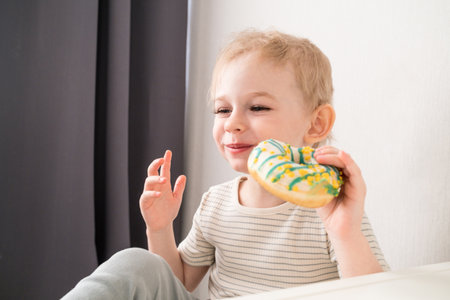 Toddler boy takes a bite of his donut.