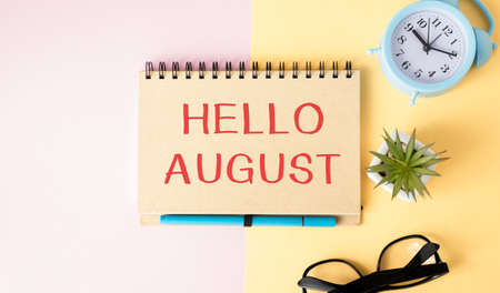 Hello August - text on a sticky note against rustic wood with a cup of coffee
