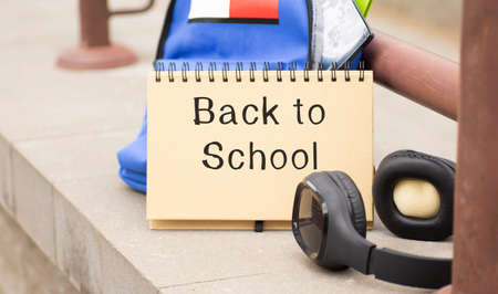 Back to school text on a notebook near a backpack and headphones.の写真素材