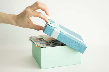 Open gift box with a big gold money coin inside on the table. Money Gift Concept.の写真素材