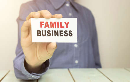 Businessman holding a card with text Family Business. Business concept.