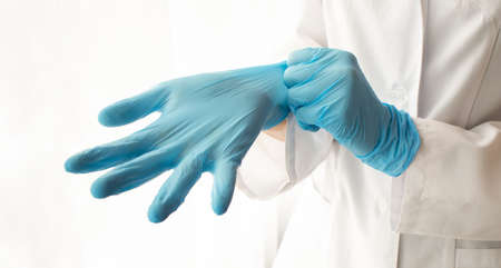 Doctor putting on protective gloves, isolated on whiteの写真素材