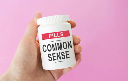 Hand holds a jar of pills, the inscription: COMMON SENSEの写真素材