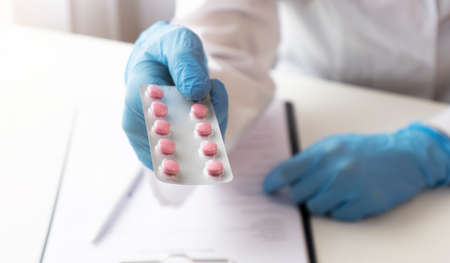 doctor holding medical drugs, pills. hands in blue latex gloves.の写真素材
