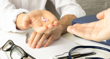 Closeup of doctor's palm holding pills for the elderly patientの写真素材