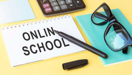 ONLIN SCHOOL inscription, glasses, notebook and pen on a yellow background. Background, copy space,...