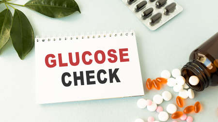 Closeup doctor hands holding white card sign with glucose check text message isolated on hospital clinic office background. Retro instagram style filter imageの写真素材
