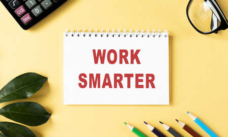 WORK SMARTER text written on a notebook with pencils and graphs.の写真素材