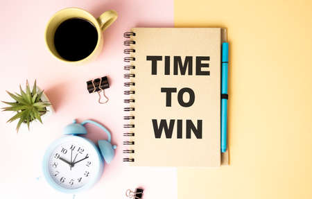 Office workplace, stationery, bright notebook and glasses. TIME TO WIN text on white notebook page. Yellow background top view, flat layの写真素材