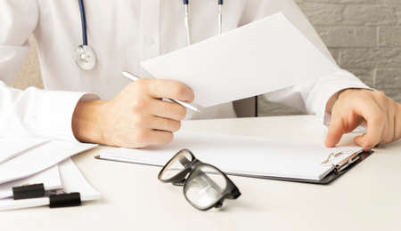 Getting ready for consultation. Dark-haired bearded doctor in a white robe looking involvedの写真素材