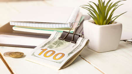 A calculator and a bundle of 100 dollars on a white background.