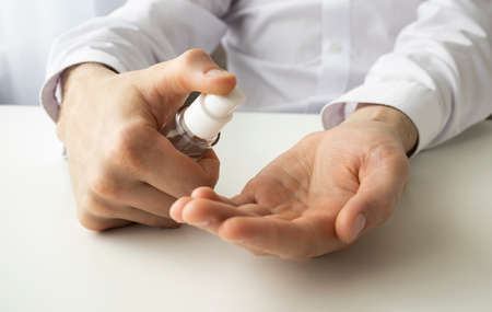 Close up male treat hand with antiseptic making disinfectant coronavirus protection. Man arm showing...