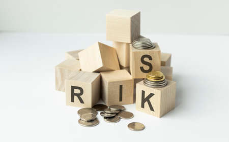 Finance concept with stack of coins, RISK written on wooden cubes.の写真素材